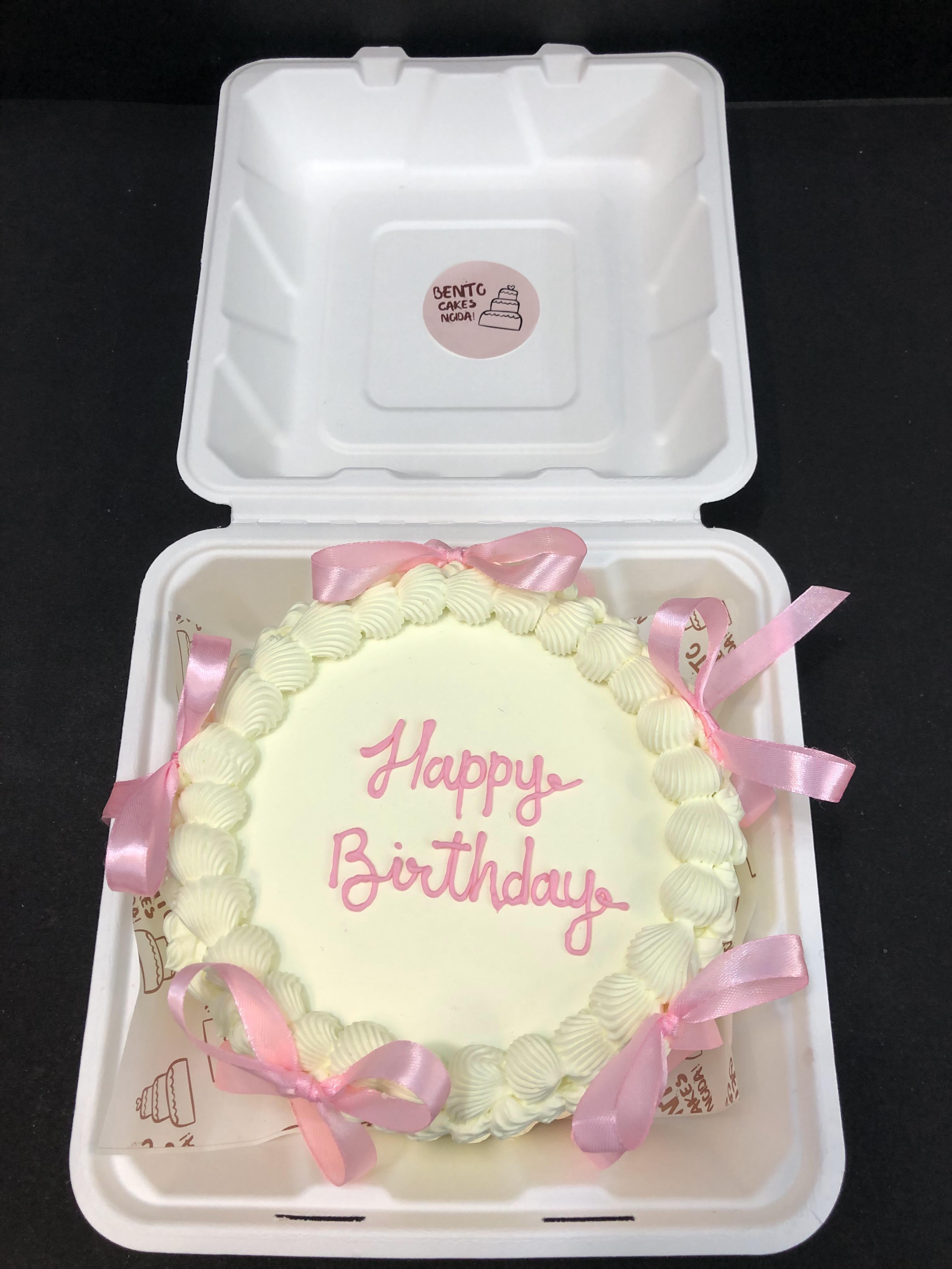 A vintage white bento cake having elegant design with light pink bows all over the cake, and is designed for birthday.