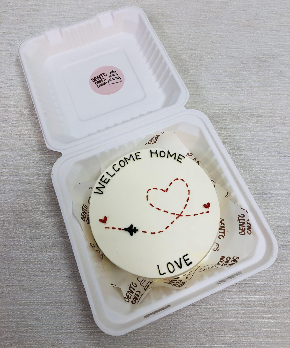 A white bento cake is designed for returning home via flight.