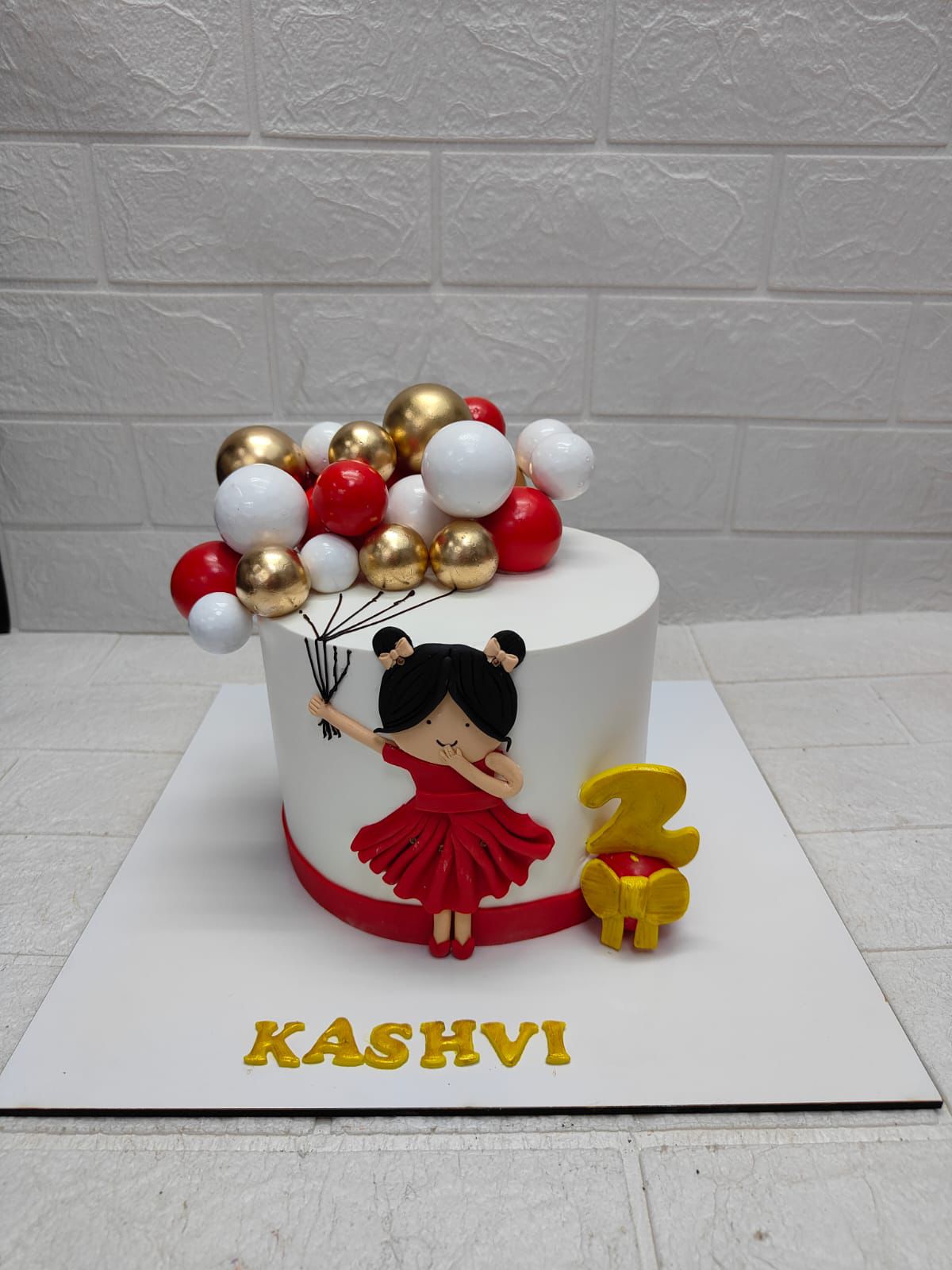 White cake with girl holding balloons