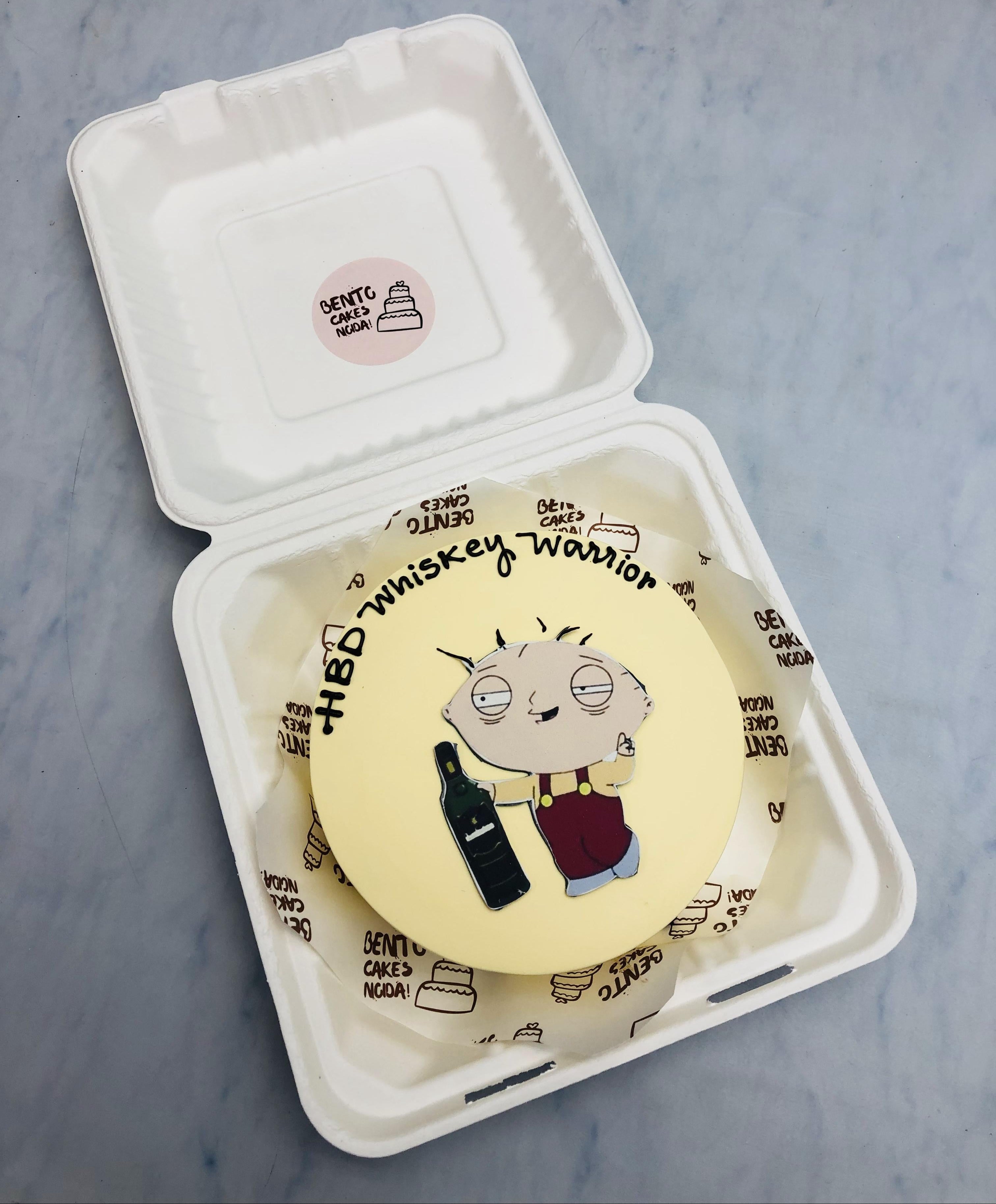 An off white bento cake with an alcoholic cartoon print enjoying his birthday.