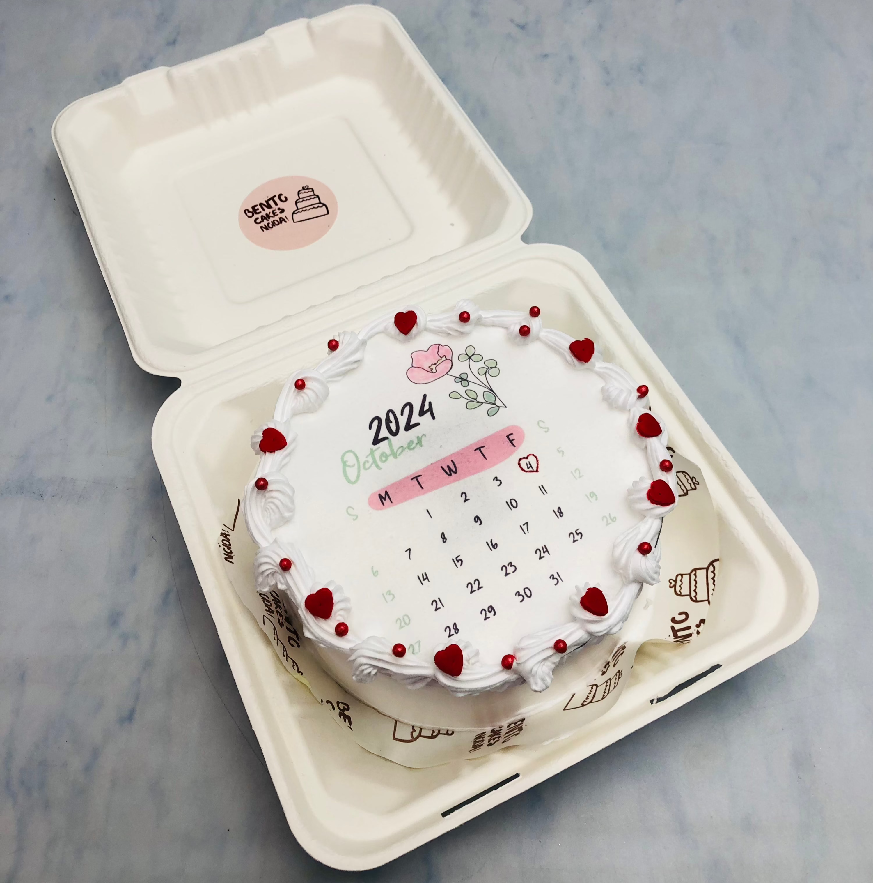 A white fire bento cake with calendar design and pretty red hearts.