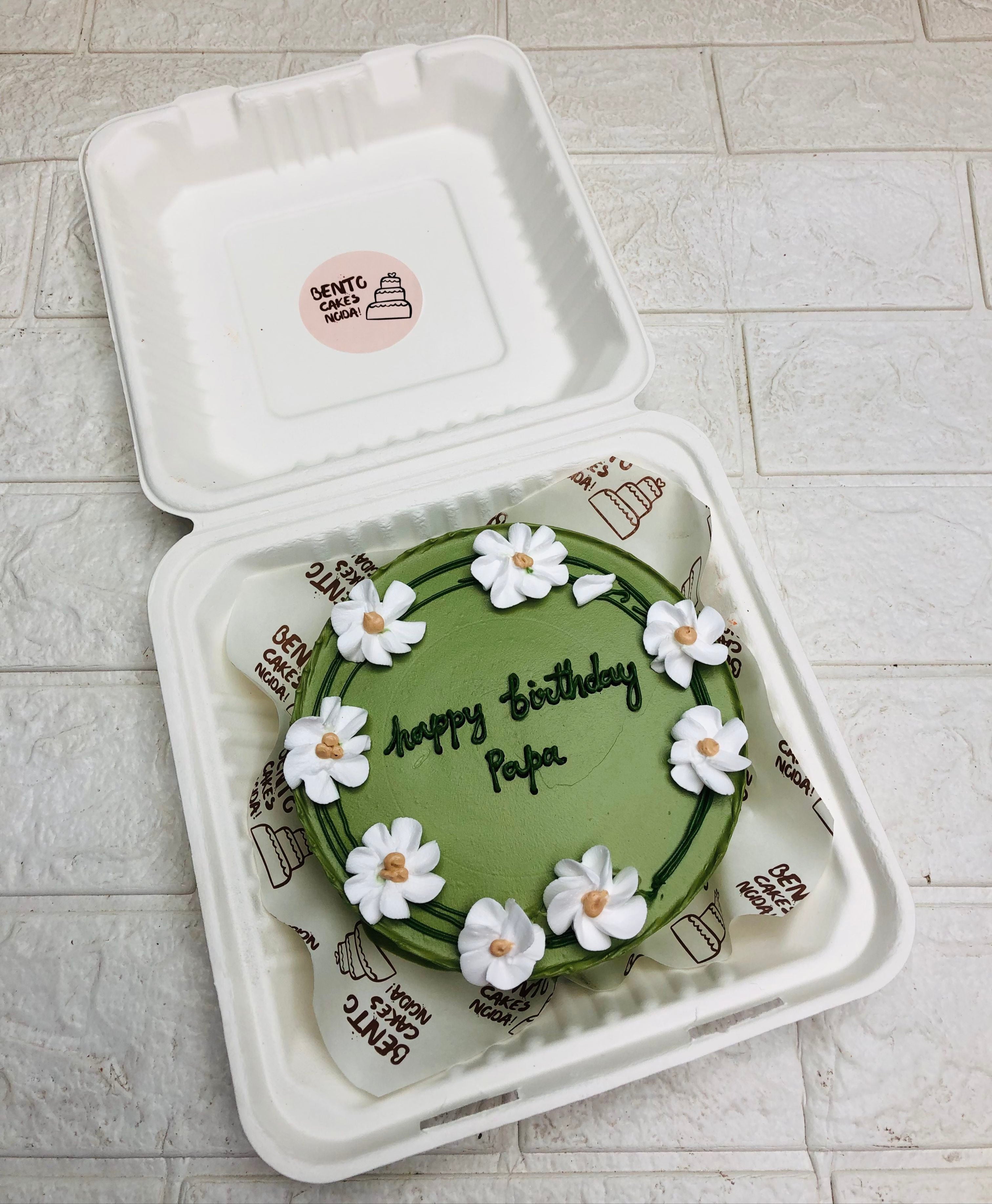 A Green bento cake is designed with White creamy Florals all over the cake for father's birthday. 