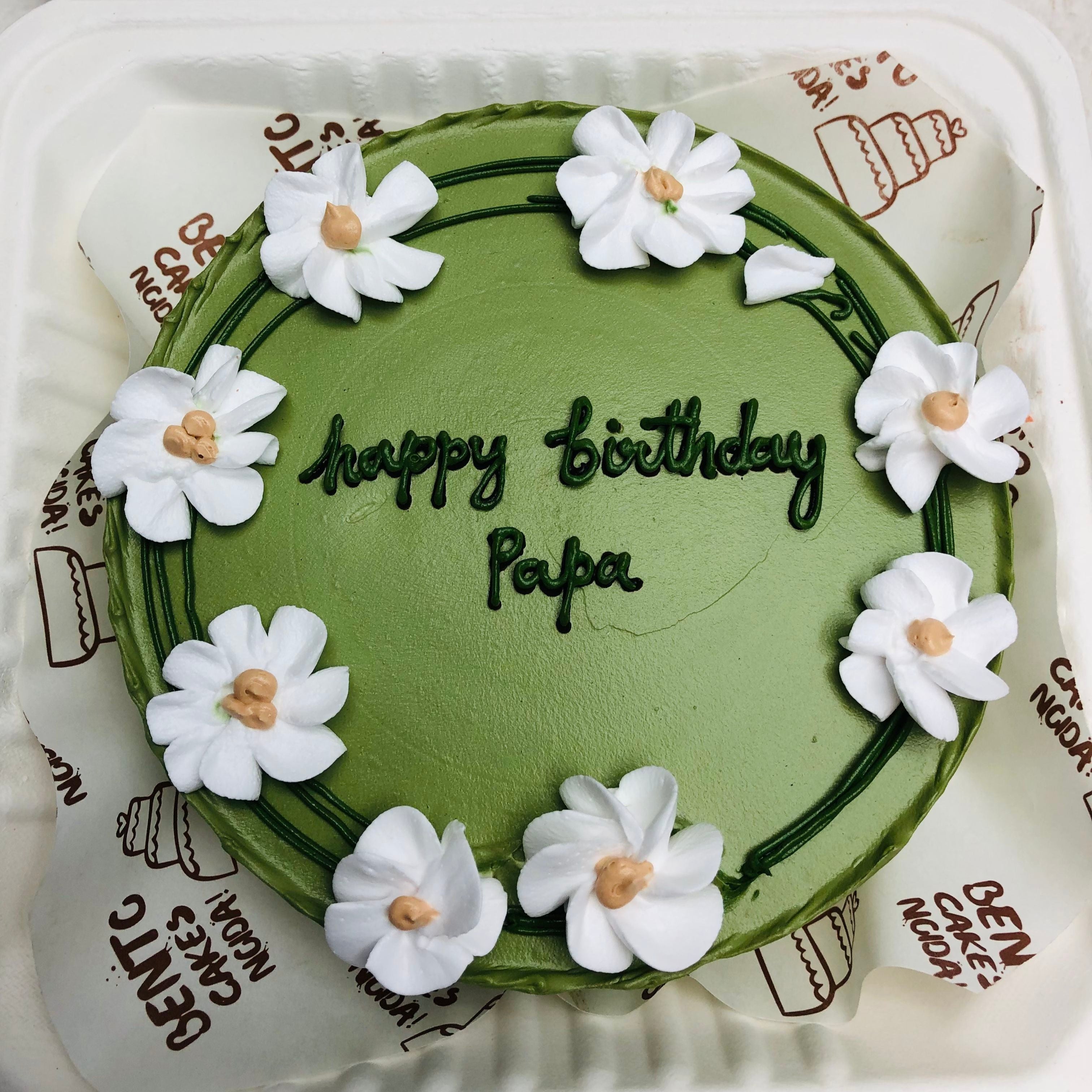 A Green bento cake is designed with White creamy Florals all over the cake for father's birthday. 