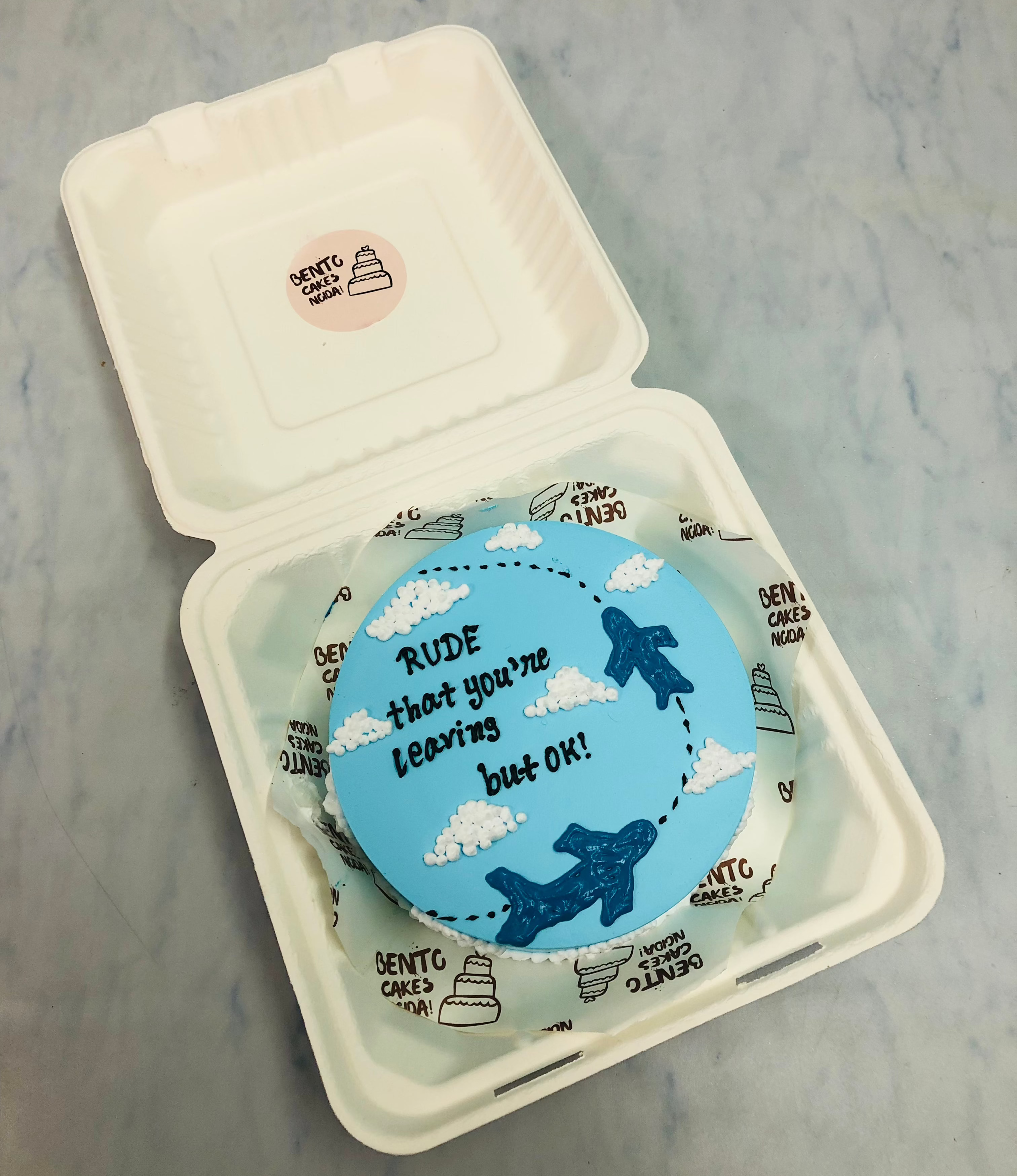 A skyblue bento cake is designed for a world traveller and a loving text written on it.