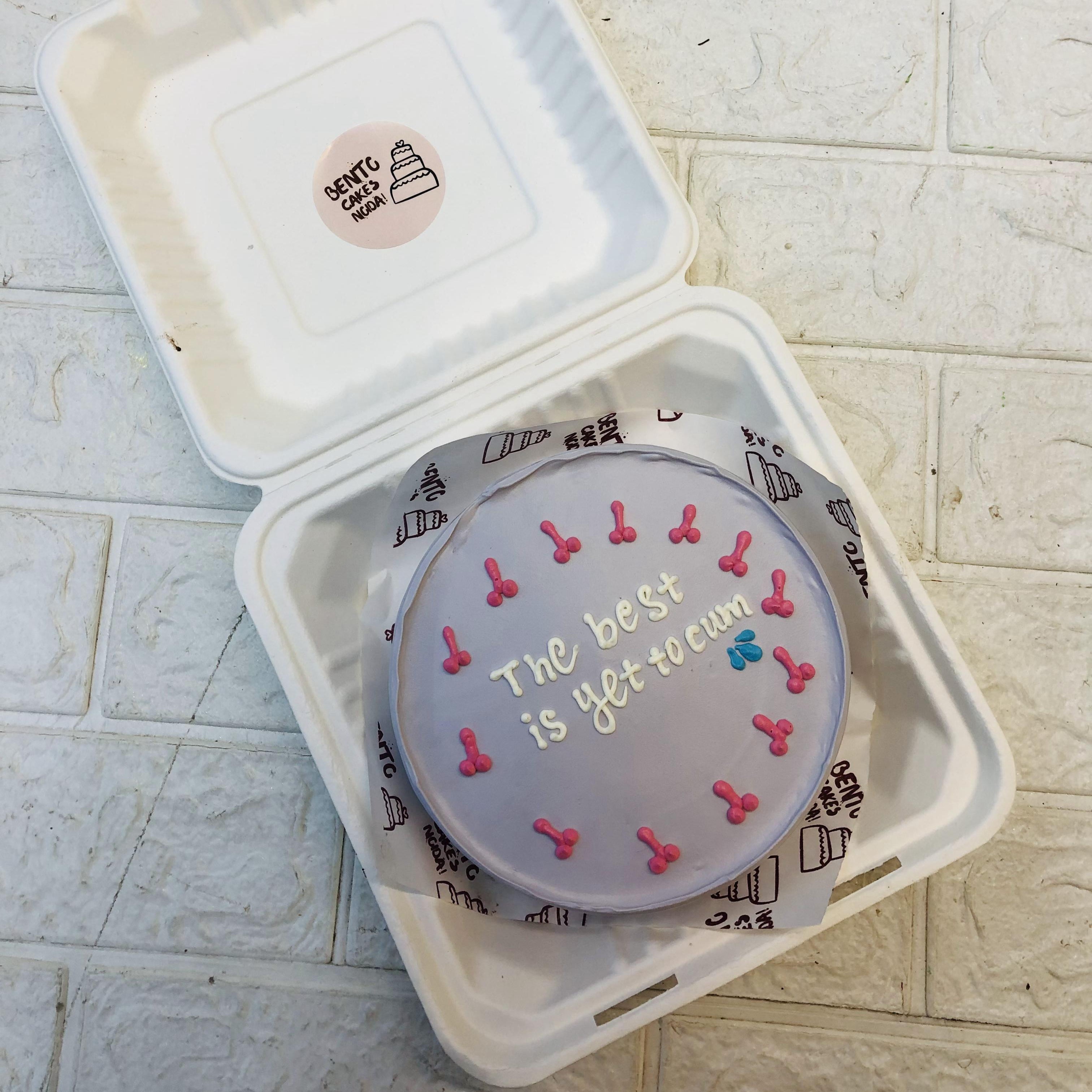A light purple bento cake with pink dick designs on its border with a bachelor text.