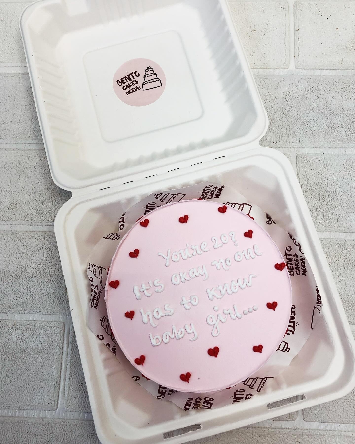 A baby pink bento cake decorated with red hearts design and a message  written with white icing.