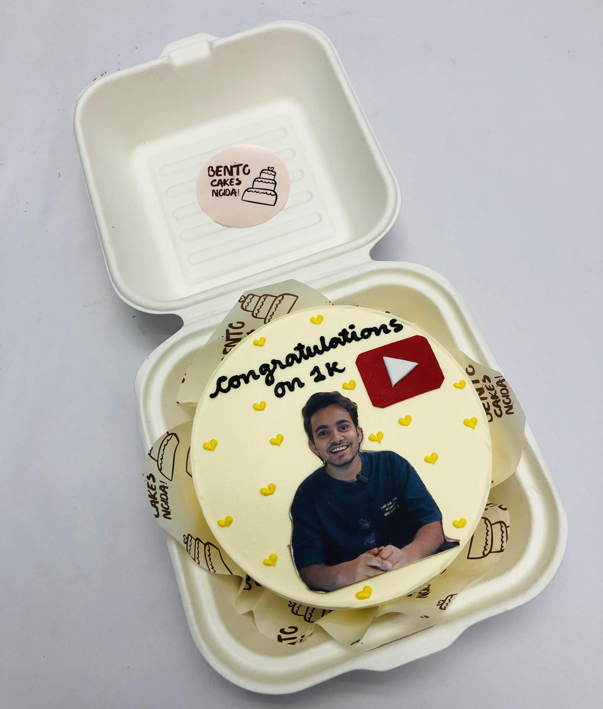 A Youtuber theme mini bento cake in offwhite color and decorated with little yellow hearts.